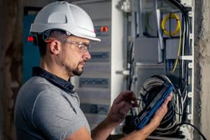 man an electrical technician working in switchboard with fuses uses tablet 1 Curso de Electricista Matriculado en Fuenlabrada